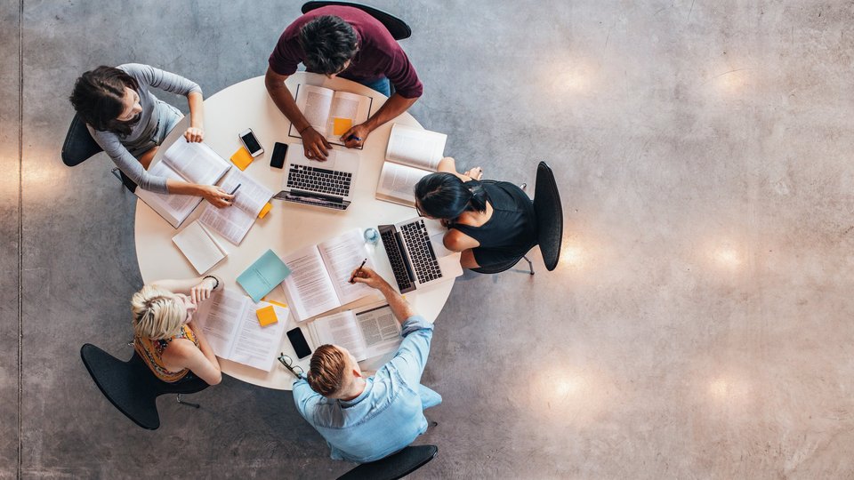 Lernende Studenten von oben an einem runden Tisch