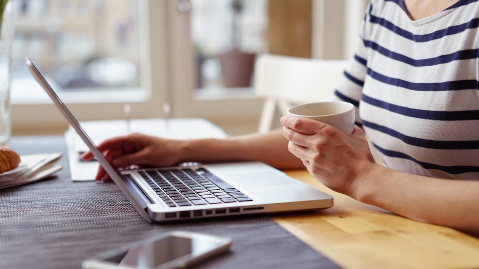 Frau mit Kaffeetasse am Notebook